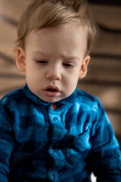 Infancia, bebé, conceptos menores - cerca de una rubia de ojos negros triste, niño ofendido bebé niño en la cama polvorienta suave en habitación soleada. retrato avergonzado preescolar niño eslavo en camisa en casa en interiores —  Fotos de Stock