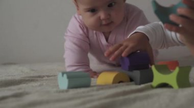 Çocukluk, aile, izolasyon, inşaat konsepti - 2 küçük mutlu çocuk yatağa oturmuş ahşap piramit inşa ediyor. 6-9 aylık yeni doğmuş kız çocuğu ve 2-3 yaşındaki oğlan evde motor becerileri için oyun oynuyorlar..