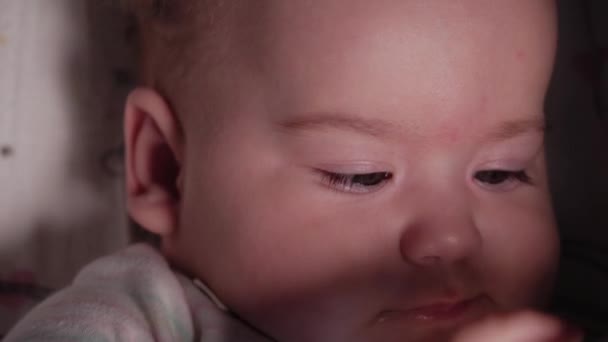 Nourrisson, enfance, concept émotionnel - Gros plan extrême du visage souriant d'un nouveau-né aux yeux bruns et sans dents bébé éveillé de 7 mois boit de l'eau du biberon avec mamelon couché en combinaison blanche dans une poussette — Video