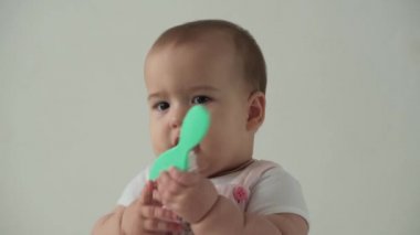 Bebek, çocukluk, hijyen, bakım konsepti. Küçük, uyanık bir çocuğun komik kahverengi gözlü tombul yüzüne yakın çekim. Saç fırçası. Mutlu Çocuk evde beyaz arka planda saç fırçasıyla kendini tarıyor..