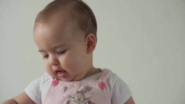 Säugling, Kindheit, Hygiene, Pflegekonzept - Nahaufnahme des lächelnden lustigen braunäugigen pummeligen Gesichts eines kleinen wachen Kindes nagt an der Haarbürste. Happy Child kämmt sich zu Hause mit Haarbürste auf weißem Hintergrund. — Stockvideo