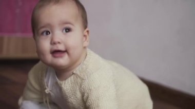 Bebek, çocukluk konsepti. Mutlu, eğlenceli, küçük bir çocuk. 8 aylık bebek, tek başına oyun odasında oynamayı öğreniyor. gülümseyen tombul aktif uyanık yeni doğmuş bembeyaz bir bebek dizlerinin üzerinde evin içinde yerde sürünüyor.