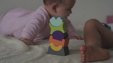 Çocukluk, aile, izolasyon, inşaat konsepti - 2 küçük mutlu çocuk yatağa oturmuş ahşap piramit inşa ediyor. 6-9 aylık yeni doğmuş kız çocuğu ve 2-3 yaşındaki oğlan evde motor becerileri için oyun oynuyorlar..