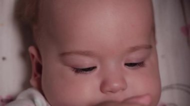 bebek, çocukluk, duygu konsepti - Kahverengi gözlü, yeni doğmuş, dişsiz bir bebeğin aşırı yakın plan gülümsemesi 7 aylık şişeden su içmesi ve bebek arabasında beyaz bir vücut giysisi içinde yatması