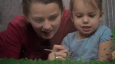 Çocukluk, annelik, yaratıcılık, doğa, sanat, bahar, yaz konsepti - 3-4 yaşlarında küçük kızı olan genç bir annenin pencere camına çizimi. Kadınlar ve anaokulu kızları çiçek boyarlar.