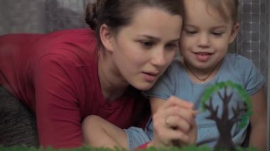 Çocukluk, annelik, yaratıcılık, doğa, sanat, bahar, yaz konsepti - 3-4 yaşlarında küçük kızı olan genç bir annenin pencere camına çizimi. kadın ve anaokulu kızı ağaç boyuyorlar..