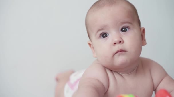 Infanzia, infanzia, genitorialità, sviluppo, medicina e concetto di salute - vista frontale primo piano nudo paffuto bambino appena nato gioiosa sveglia in tuta rosa sorridente con giocattolo multicolore sdraiato sulla pancia — Video Stock