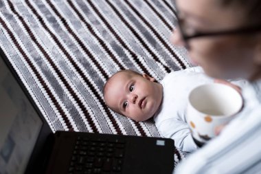 Çocukluk, annelik, aile kavramları başarılı gülümseyen zengin iş kadını anne kucağında bebek bebekle evde uzaktan bilgisayarla telefonda konuşuyor.