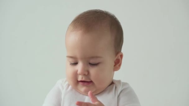 Немовля, дитинство, концепція гігієни крупним планом усміхнене щасливе кумедне пухке обличчя маленької дитини прокинулося. Радість беззубика 7 місяців дитина вперше чистить зуби блакитною щіткою на білому тлі — стокове відео