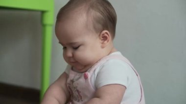 Bebek, çocukluk konsepti. Mutlu, komik, küçük bir çocuk. 8 aylık bebek kız, oturup tahta ve kablo boncuklu abaküs oyunu oynuyor. Tombul uyanık yeni doğmuş bebek oyun odasında, evde yerde sürünüyor.