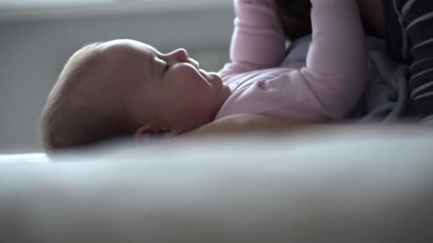 Geneeskunde, gezondheidszorg, familie, onschuld, kindergeneeskunde, geluk, baby concepten - Jonge gelukkige moeder spelen met naakt 9 maanden baby, massages, kussen, strelingen zitten in fel zonlicht kwekerij op bed — Stockvideo