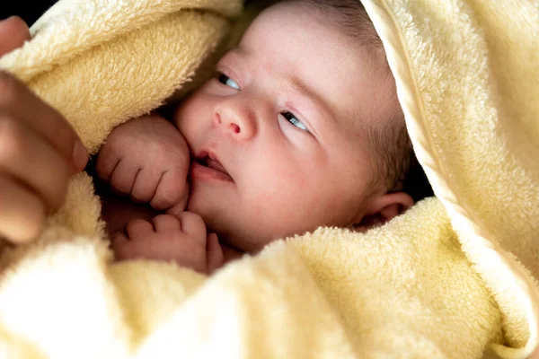 Dětství, péče, hygiena, mateřství, koncepce nevinnosti - Close up Mokré probuzení Novorozenec po sprchování zabalený do teplého žlutého ručníku při pohledu na fotoaparát saje drobné prsty. babys první koupel — Stock fotografie