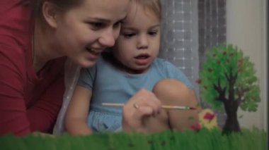 Çocukluk, annelik, yaratıcılık, doğa, sanat, bahar, yaz konsepti - 3-4 yaşlarında küçük kızı olan genç bir annenin pencere camına çizimi. kadın ve anaokulu kızı ağaç boyuyorlar..