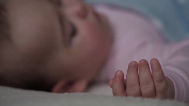 Bebeklik, Rahatlama, Tatlı Rüyalar, Annelik, Aile Konsepti - bebek minicik ellerini rüya gibi ellerle hareket ettir. 9-12 aylık küçük çocuk battaniyeyle kaplı beyaz yatakta uyuyor. Öğle Yemeği Uyku Kipi