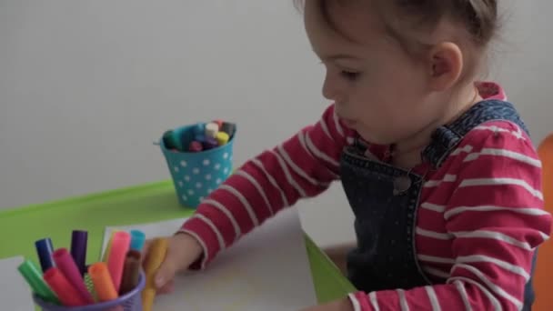 Art, éducation, enfance, concepts - Petite petite fille heureuse de 3 ans de maternelle intelligente dessine avec des stylos à pointe de feutre et des crayons assis à table dans la chambre à la maison. enfant intelligent peint à l'intérieur — Video