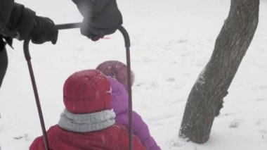 Kış, çocukluk, babalık, oyunlar, aile kavramları - kapanış iki mutlu anaokulu çocuğu kardeş kızakla kayarak eğleniyorlar babayla birlikte buz gibi havada parkta oynuyorlar.