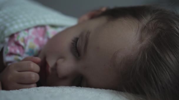Релаксація, солодкі мрії, дитинство, концепції сім'ї - щільно крупним планом Маленька 3-річна маленька дошкільнята мокра дівчинка спить на білому ліжку, покритому ковдрою в темній кімнаті в режимі сну — стокове відео
