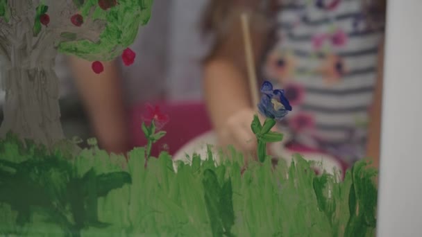Dzieciństwo, kreatywność, natura, wiosenna, letnia koncepcja - zbliżenie dwójki małych przedszkolaków rysujących akrylowym kolorem na szybie okna. rodzeństwo brat z siostra malować krajobraz: drzewo, trawa — Wideo stockowe