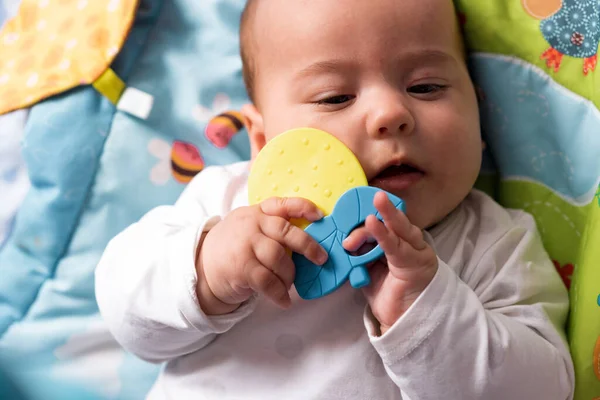 Childhood, happiness, motherhood concepts - Infant surprised, funny newborn child baby aged 3-4 months playing with toys, gnawing toothpicks on developmental mat lying on stomach at home indoors — Stock Photo, Image