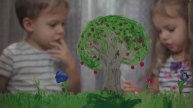 Çocukluk, yaratıcılık, doğa, ilkbahar, yaz konsepti - pencere camına akrilik renk çizen iki küçük anaokulu çocuğunun yakın çekimi. Kardeşlerin çocukları ve kız kardeşlerin manzara resimleri: ağaç, çimen