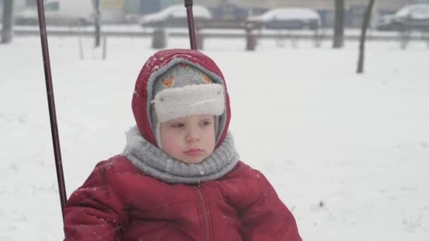 Infanzia, paternità, giochi, concetti di famiglia - chiudere un triste, sconvolto bambino in età prescolare bambino minore ragazzo figlio in caldi vestiti invernali slittino sedersi su slitta in nevicata freddo tempo nel parco all'aperto — Video Stock