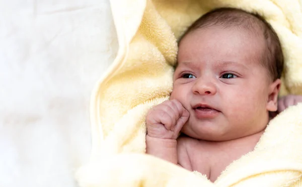 Çocukluk, bakım, hijyen, annelik, masumiyet kavramları - Sıcak sarı havluya sarılıp kameraya baktıktan sonra ıslak, uyanık, yeni doğmuş bir bebek. İlk banyo bebekler için. — Stok fotoğraf