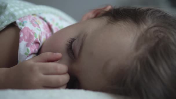 Расслабление, сладкие сны, детство, семейные конфузы - маленькая трехлетняя дошкольная девочка спит на белой кровати в одеяле в темной комнате в обеденное время — стоковое видео