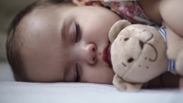 幼児、リラクゼーション、甘い夢、子供時代、家族のコンセプト- Athetic Little 9-12ヶ月の顔をしっかりと閉じてください幼児の女の子ランチタイムスリープモードで毛布に覆われた白いベッドで寝る. — ストック動画