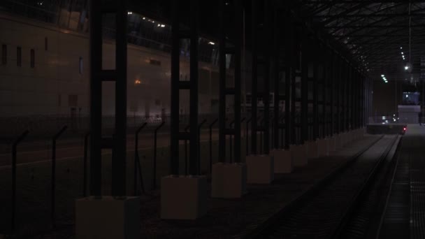Transportasi, perjalanan, jalan, kereta api, konsep comnication Pemandangan umum stasiun kereta api kosong dekat bandara Boryspil di Kiev pada malam hari. Struktur logam melengkung di atas depot penumpang tanpa orang — Stok Video