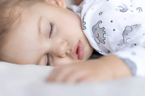 Gyermekkor, gondozás, anyaság, egészség, gyógyszer, gyermekgyógyászati fogalmak - Close up Kis béke nyugodt kisgyermek óvodás alszik pihen mély szundikálás feküdt a has puha ágyon. lefekvés előtti mod közeli szemek — Stock Fotó