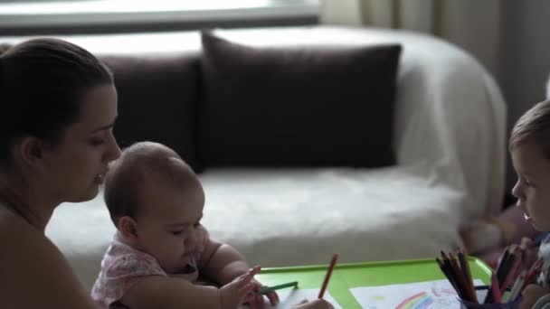 Enfance, Art, éducation, Créativité, concept de maternité - authentique jeune maman avec deux enfants préscolaire créatif talentueux garçon enfant 2-4 ans et bébé dessine des peintures par crayons image assis à la table — Video