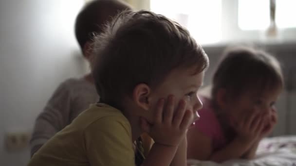 Familie, vrije tijd, jeugd, vriendschap concepten - authentieke drie jonge kleuter kleuter minderjarige kinderen kinderen kinderen broers en zussen kijken cartoon op smartphone telefoon apparaat samen op de bank in de kamer thuis — Stockvideo