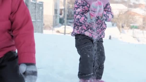 冬、休暇、ゲーム、家族のコンセプト- slo-mo帽子をかぶった2人の幸せな就学前の幼児の兄弟とお母さんが手で雪を投げて遊ぶミトン。屋外の公園の寒い季節の天気で — ストック動画