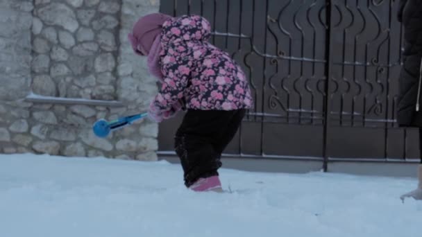 Winter, vakantie, spelletjes, familieconcepten - verre schot van authentieke kleine kleuter 3-4 jaar oud meisje in het paars op besneeuwde weide speelt met Sneeuwbal Clip buiten. kind loopt op besneeuwd gebied — Stockvideo