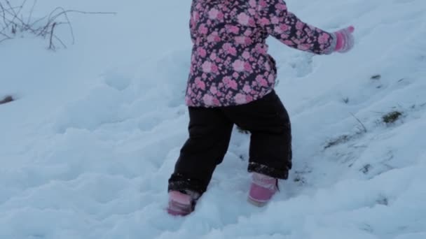 Inverno, vacanza, gioco, concetto di famiglia - slow motion close up baby walk through deep snow. i piedi dei bambini camminano su un sentiero innevato. bambino in età prescolare vestito di tuta nera in nevicata nella stagione fredda — Video Stock