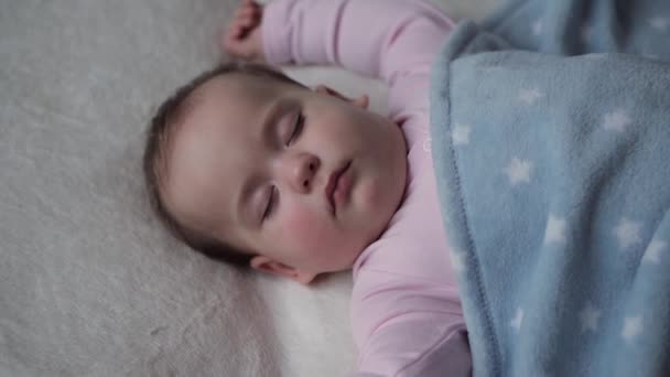 Младенчество, релаксация, сладкие сны, детство, семейная концепция - пухленькое милое личико маленькой 9-12 месяцев, новорожденный ребенок девочка спит на белой кровати, покрытой голубой одеяло. Обеденный сон — стоковое видео