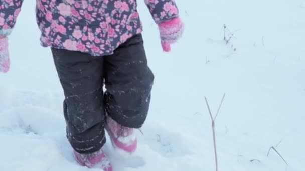 Winter, Urlaub, Spiele, Familienkonzept - Slow-mo-Kinderlauf durch tiefen Schnee. Kinderfüße treten auf verschneiten Pfaden. Vorschulkind in schwarzem Overall bei Schneefall in der kalten Jahreszeit — Stockvideo