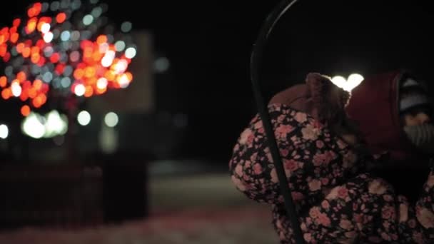Tél, nyaralás, játékok, családi koncepciók - autentikus Két boldog óvodás kisgyerek testvérek öltözött kalap és kesztyű anya játszik ülni szánkó a parkban hideg évszakban időjárás éjjel szabadban — Stock videók