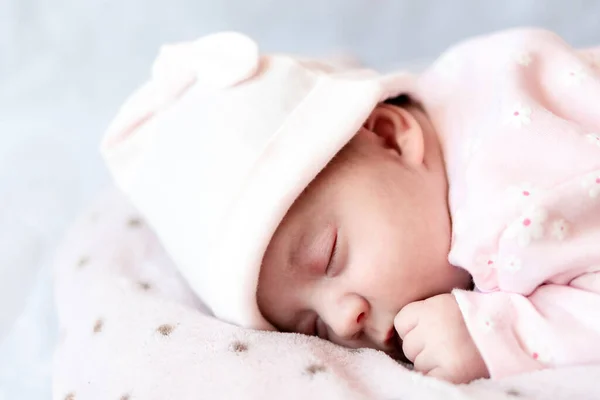 Infanzia, cura, maternità, concetti di salute - Close up Piccola pace calma neonata in cappello rosa dorme riposando fai un pisolino profondo sdraiato sulla pancia su una morbida coperta calda nido pilow con occhi ravvicinati — Foto Stock