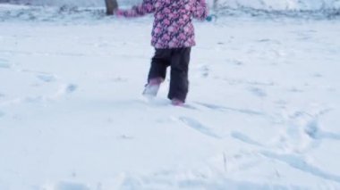 Kış, tatil, oyunlar, aile kavramları. Küçük, otantik anaokulu öğrencilerinin orta planı. Mor elbiseli kız, karla kaplı çayırda kırsalda karla oynuyor. çocuk karlı alanda koşar.