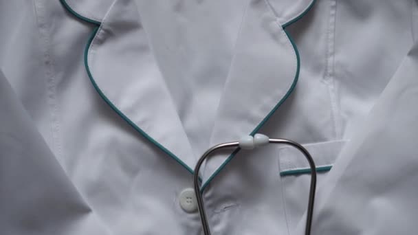 Medicin och hälsa, pediatrik, covid-19 koncept - närbild vit medicinsk klänning och stetoskop. sjuksköterska eller läkare kostym grejer. Förberedelser för operation. Coronavirus pandemisk fara. sjukhusatmosfär. — Stockvideo