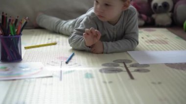 Çocukluk, Sanat, Eğitim, Yaratıcılık Konsepti - otantik anaokulu zeki yaratıcı çocuk 2-4 yaşında renkli kalemlerle aile baharı, paspas zeminde gökkuşağı resimleri çiziyor