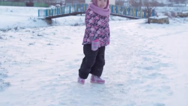 Invierno, vacaciones, juegos, concepto familiar: plan medio de una auténtica niña de 3 a 4 años de edad preescolar en púrpura en un prado cubierto de nieve juega con nieve antes del atardecer. niño corre en la zona nevada — Vídeos de Stock