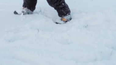 Kış, tatil, oyunlar, aile kavramı. Yakın çocuk derin karda yürür. Çocuklar karlı yolda yürür. Anaokulu çocuğu kardeşler, soğuk mevsimde kar altında siyah tulum giymişler.