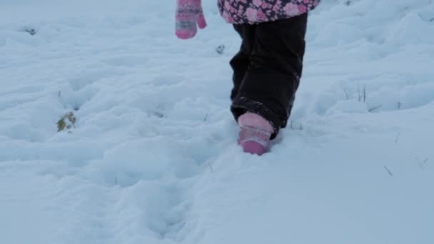 Winter, Urlaub, Spiel, Familienkonzept - Zeitlupe hautnah Babyspaziergang durch tiefen Schnee. Kinderfüße treten auf verschneiten Pfaden. Vorschulkind in schwarzem Overall bei Schneefall in der kalten Jahreszeit — Stockvideo