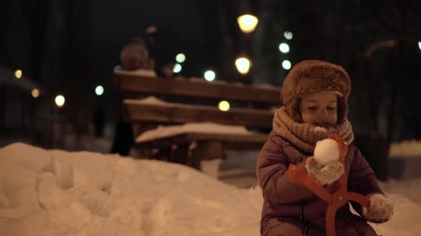 Tél, nyaralás, játékok, családi koncepciók - középső terv autentikus boldog kis óvoda Toddler testvérek gyerekek érezzék jól magukat az esti parkban, szobrászat hógolyók esik hóterületen hideg fagyos időben — Stock videók