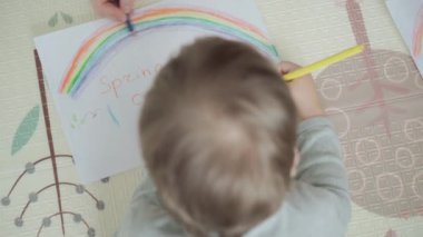 Otantik iki mutlu kardeş yaratıcı çocuklar anneleriyle birlikte kalemle çiziyorlar bahar geliyor resim gökkuşağı içeride, oyun odasında yerde eğleniyor. Çocukluk, Sanat, Eğitim, Yaratıcılık, annelik kavramı