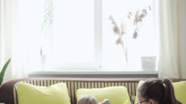 Çocukluk, aile, annelik, ebeveynlik kavramı. Genç mutlu anne mıknatıs blokları oynamaktan zevk alıyor. Bebeklerle kale inşa ediyor. Üç çocuk karantinadaki oyun odasında birlikte eğleniyor.