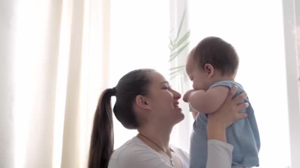 Authentic close up shot of young neo caucasian mother keeping in arms and caressing newborn baby in nursery in morning. infant, maternity, motherhood, parenthood, childhood, life, authenticity concept — Stock Video