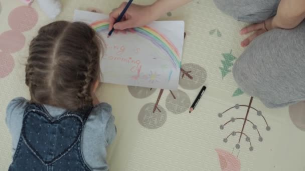 Authentique deux enfants créatifs heureux frères et sœurs tout-petits avec maman dessiner par crayons printemps image à venir arc-en-ciel amusez-vous sur le sol à l'intérieur dans la salle de jeux. Enfance, Art, éducation, Créativité, concept de maternité — Video